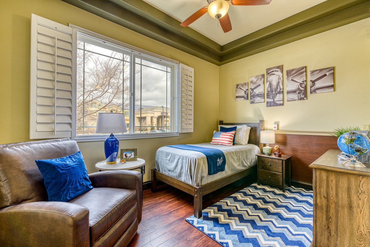 A cozy bedroom with a single bed, armchair, and colorful decor.