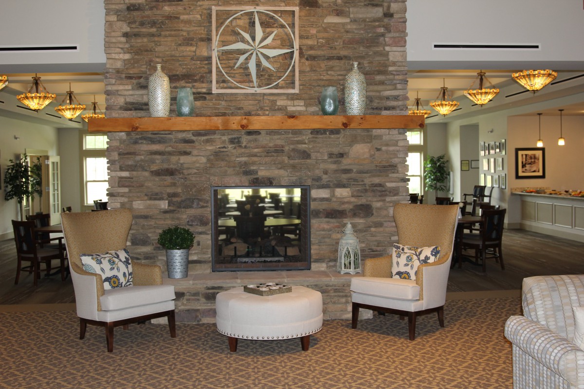 A cozy living room featuring a stone fireplace, comfortable chairs, and stylish decor.