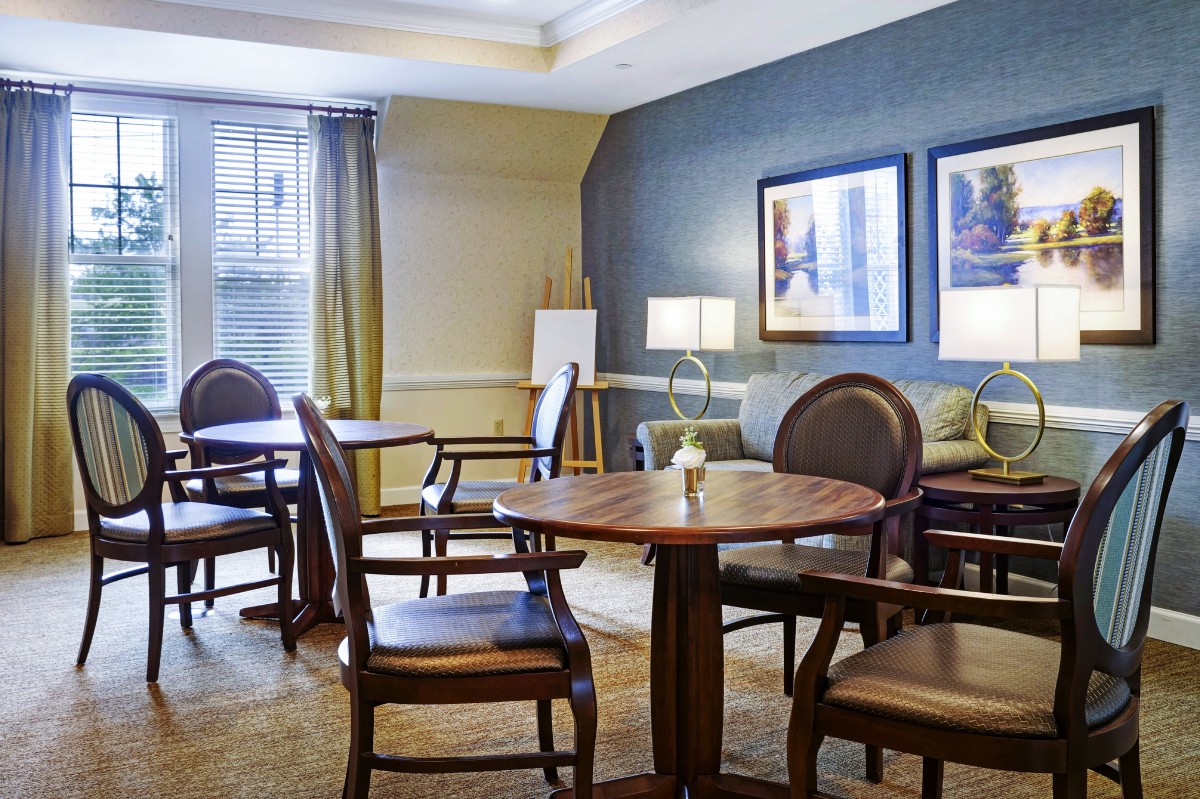 A cozy meeting room with tables, chairs, and artwork on the walls.