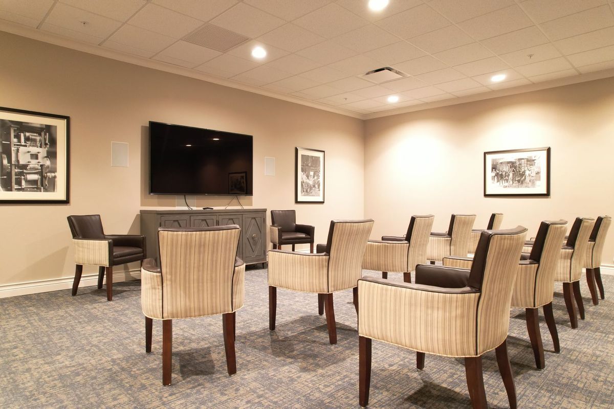 A conference room with arranged chairs and a TV screen, ready for a meeting.