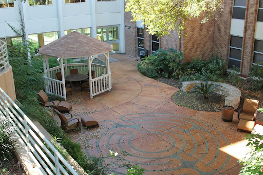A serene courtyard featuring a gazebo surrounded by lush greenery and a patterned walkway.