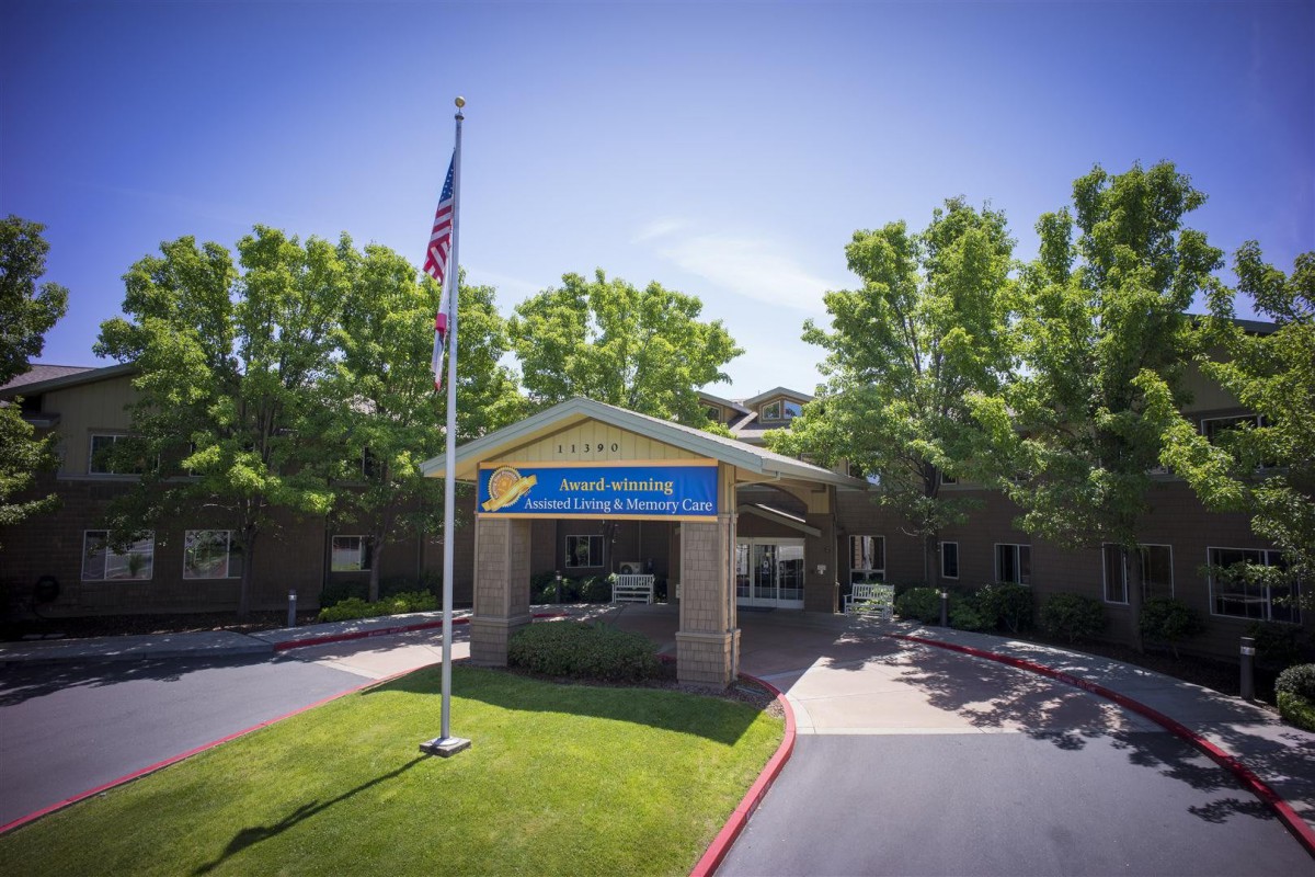Entrance of a building with an American flag and surrounding trees.