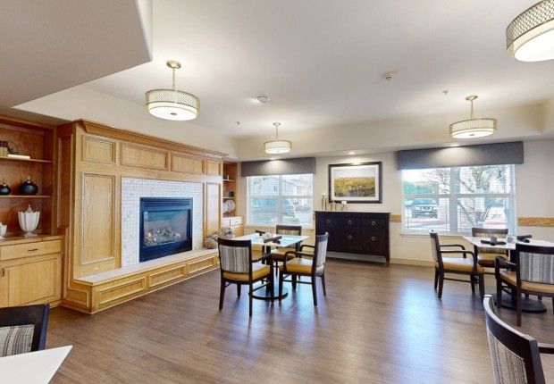 A cozy living room with a wooden floor, featuring a fireplace, seating area, and elegant decor.