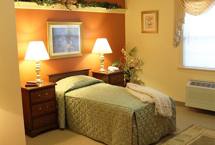 A cozy bedroom with a single bed, warm lighting from lamps, and decorative elements.