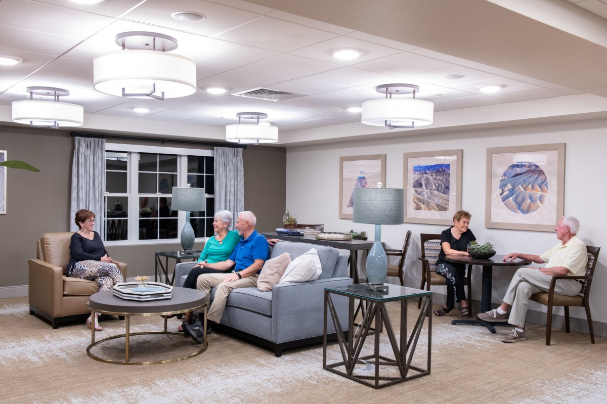 A cozy living room with several people seated on sofas, enjoying a relaxed atmosphere under modern lighting.