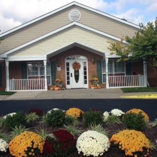 A building with a landscaped garden featuring colorful flowers at the entrance.