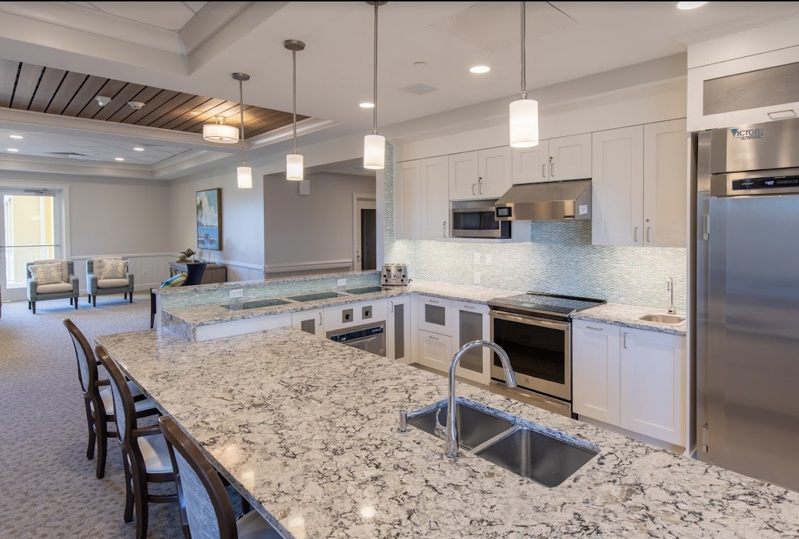A modern kitchen with granite countertops, stainless steel appliances, and pendant lighting.