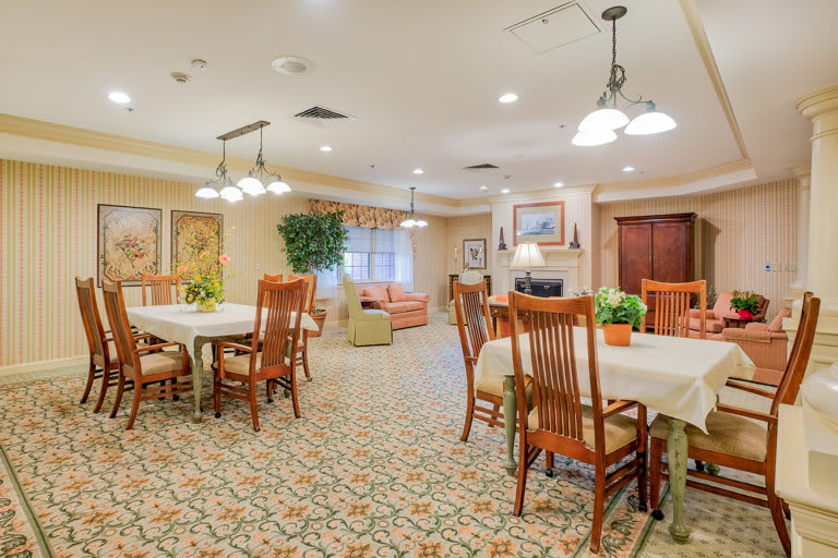 A cozy dining area with wooden tables and chairs, warm lighting, and elegant decor.