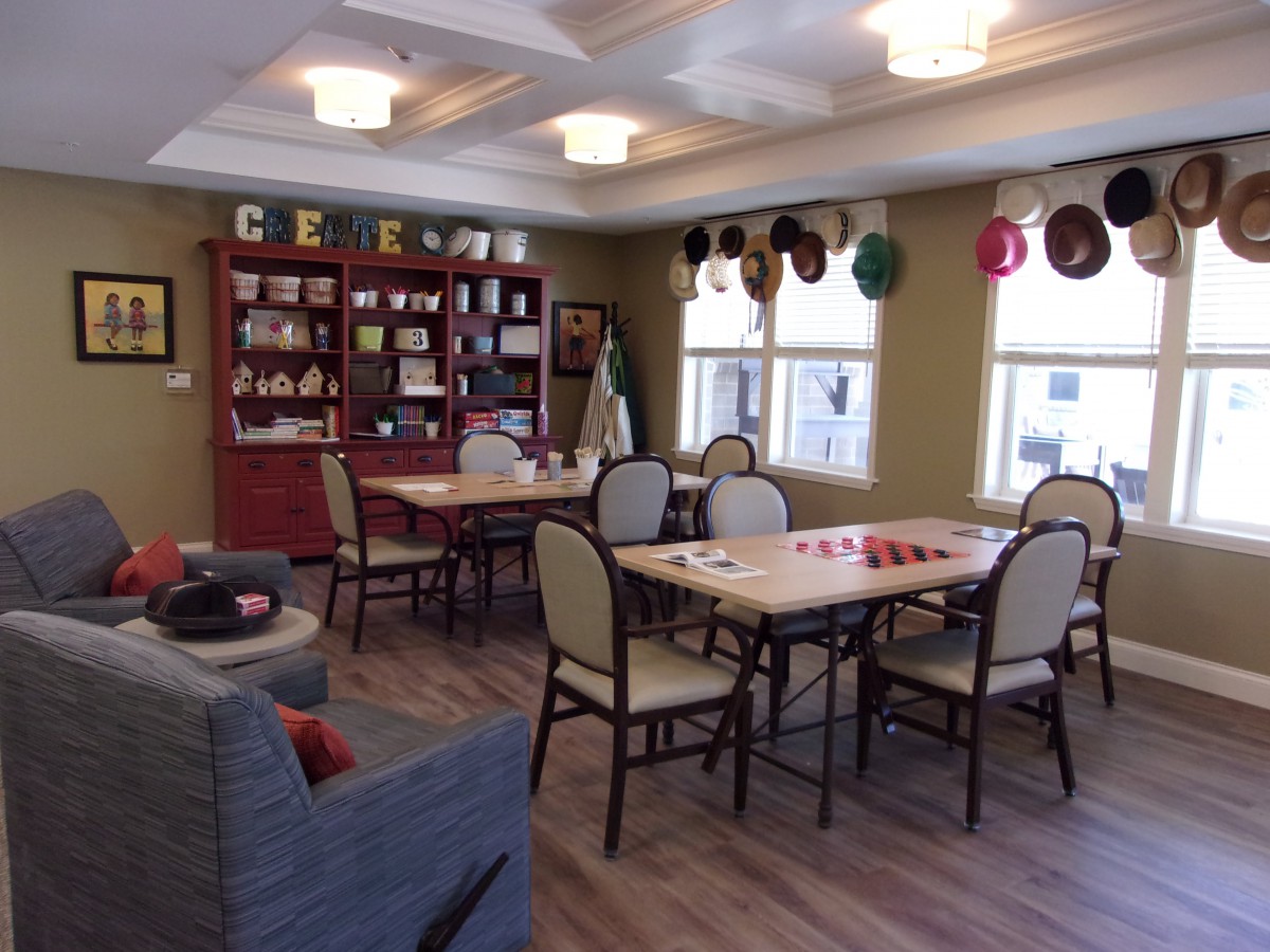 A cozy community dining area with tables, chairs, and decorative hats on the walls.