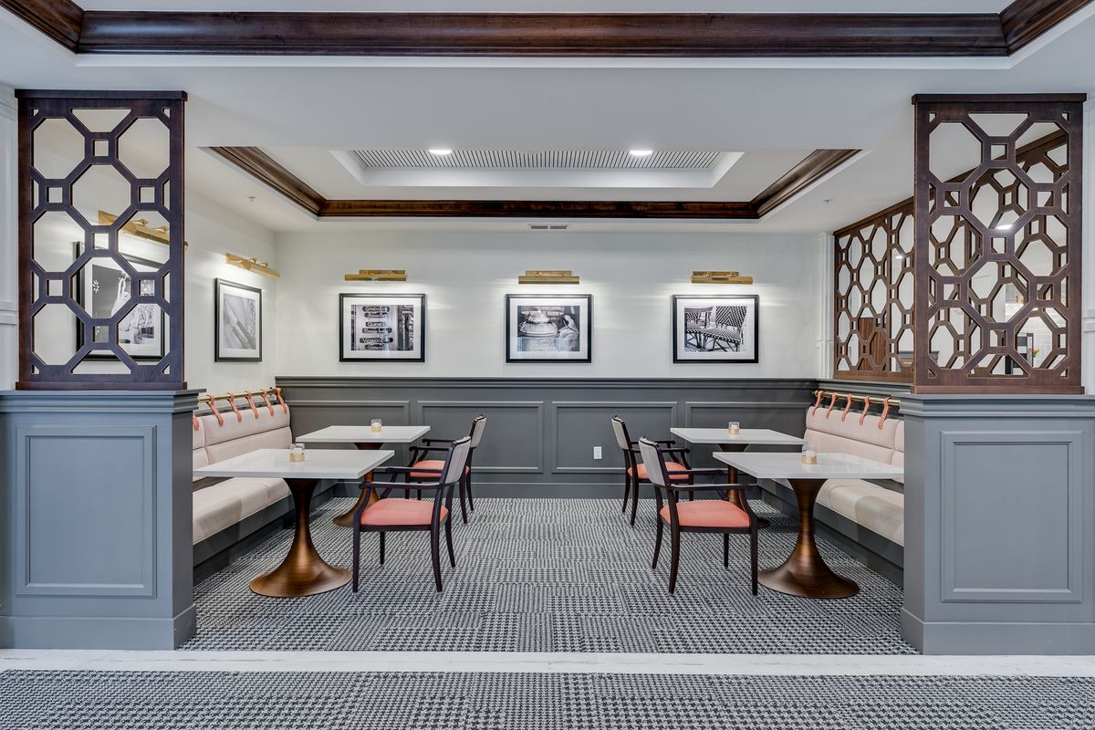 A stylish cafe interior featuring framed artwork and a cozy seating area with tables and chairs.