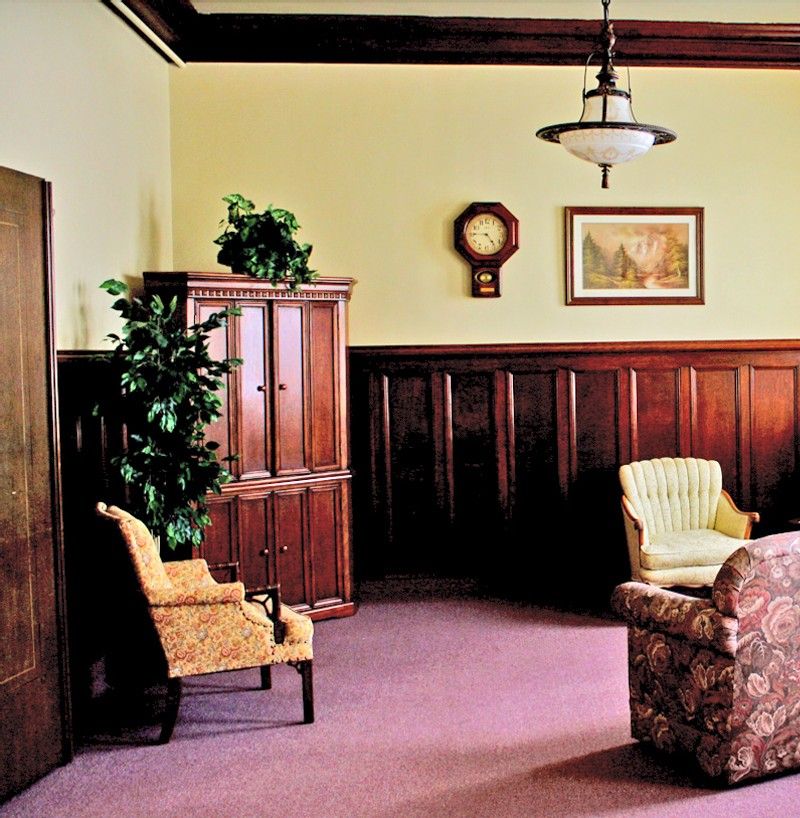 A vintage-style living room with retro furniture, featuring wood paneling and a classic clock on the wall.