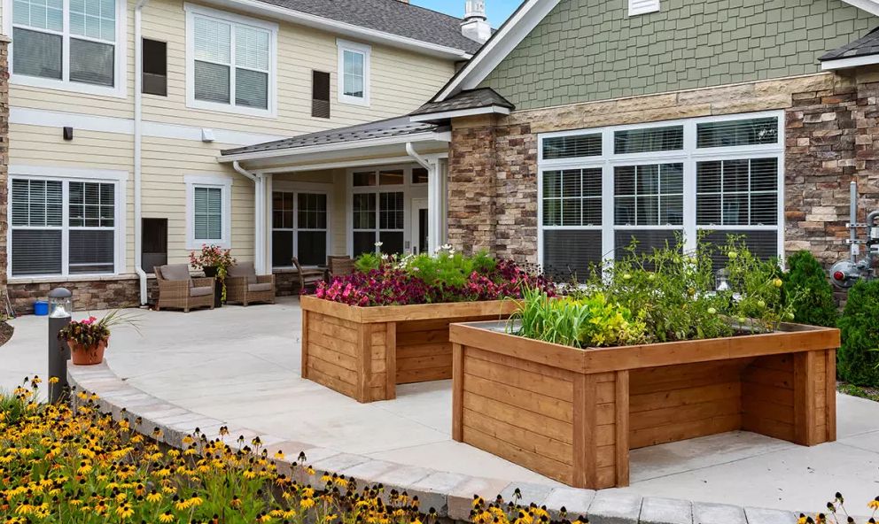 A charming residential patio featuring raised planter boxes filled with vibrant flowers.