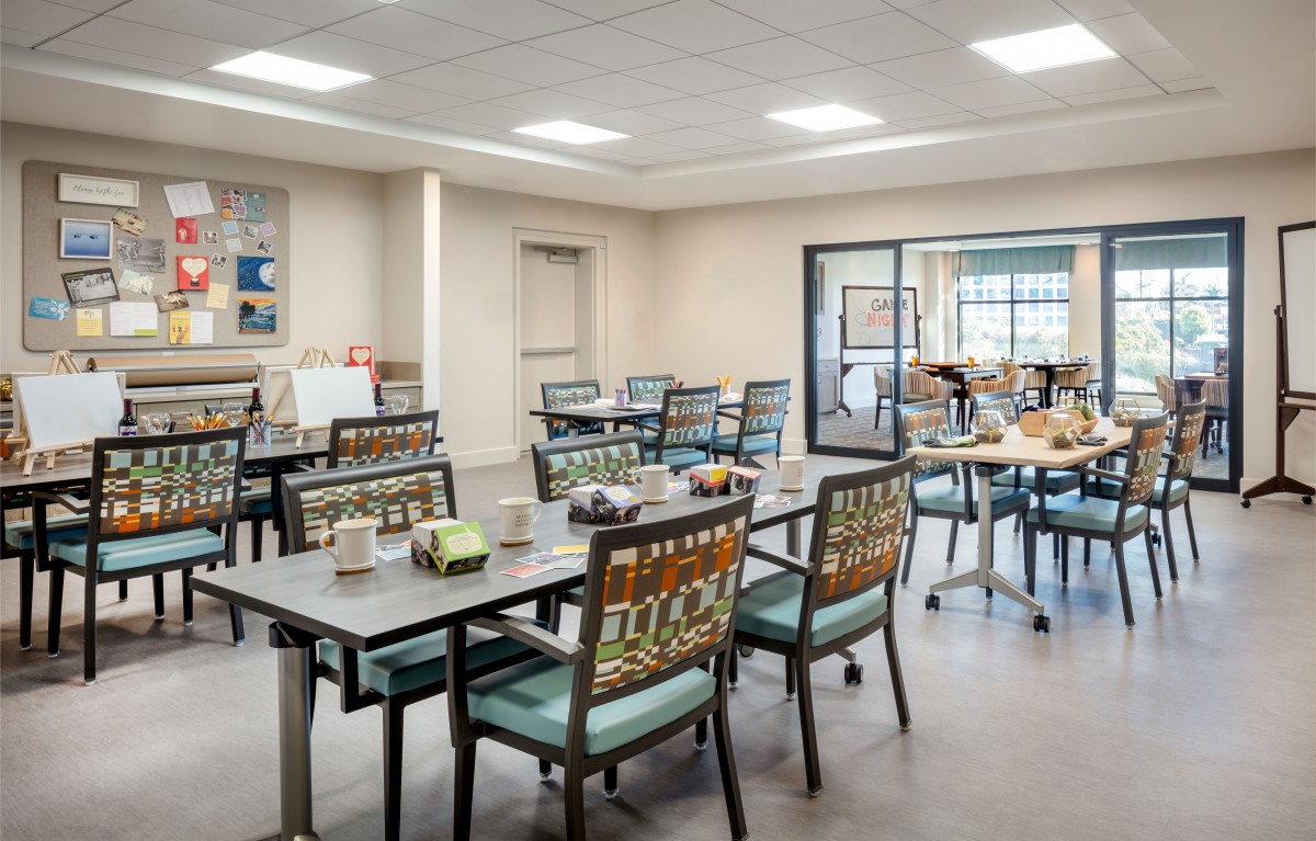 A well-lit community dining area with arranged tables and chairs.