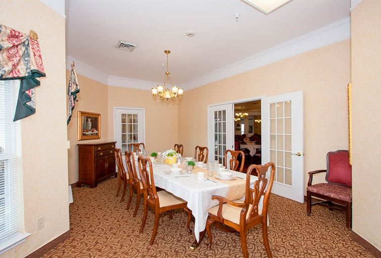 An elegant dining room with a long table set for guests and surrounded by wooden chairs.