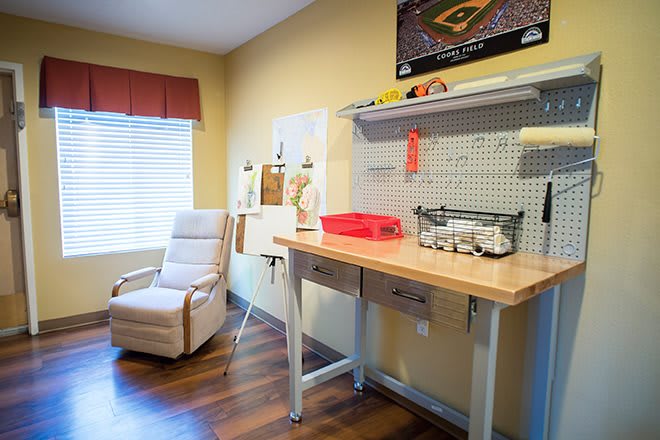 A well-organized home office with a desk, chair, and pegboard for storage.