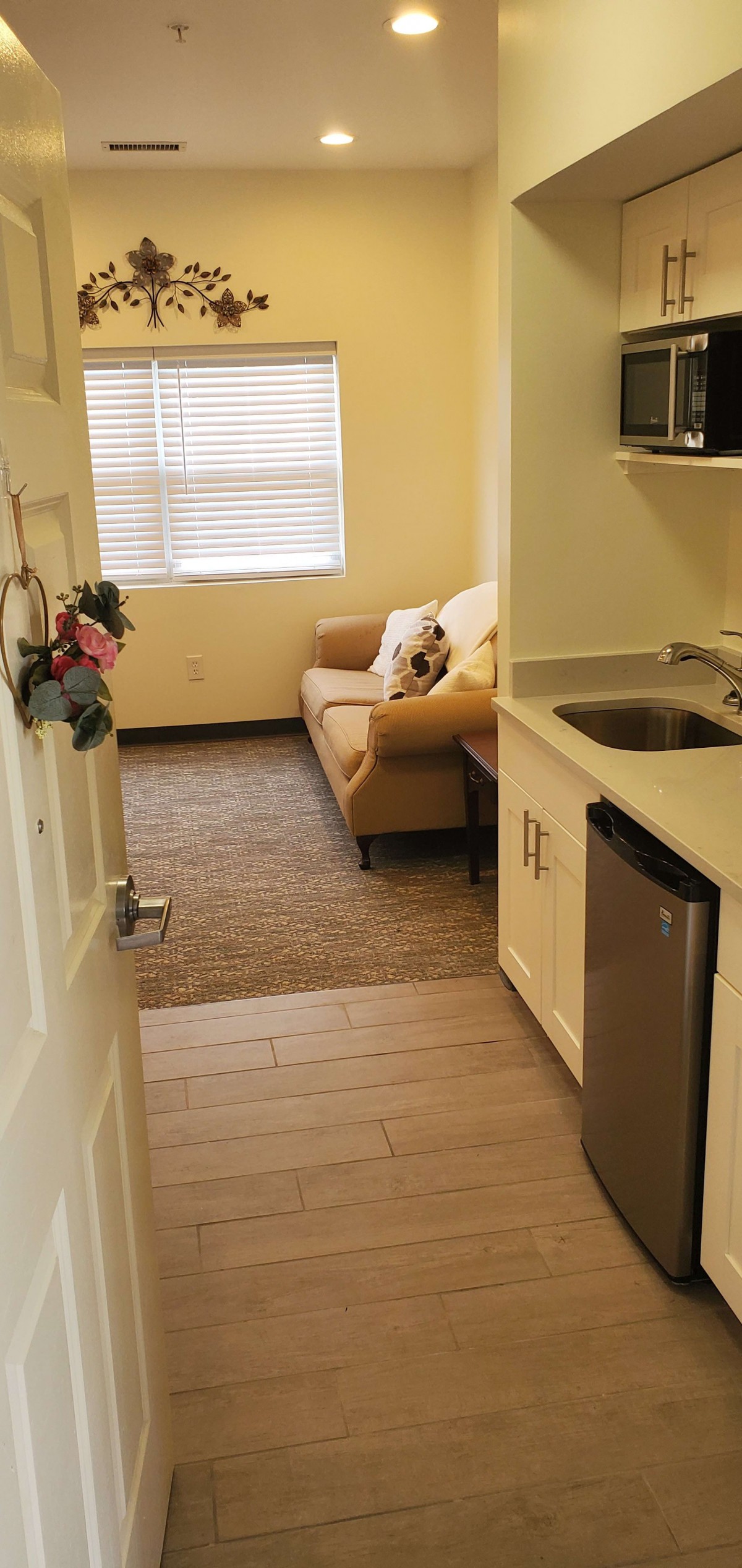 A cozy apartment with a small kitchenette and a living room featuring a comfortable sofa.