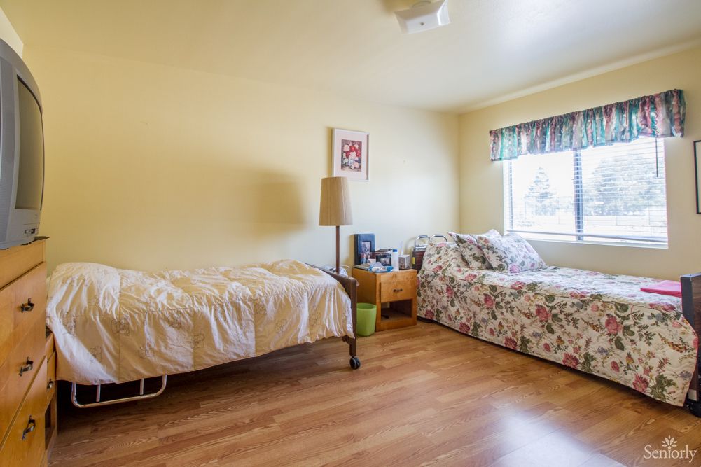 A cozy bedroom with a single bed and wooden flooring, featuring a window and minimalistic decor.