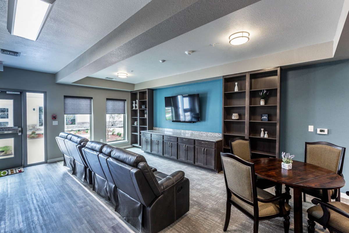 A modern living room featuring a home theater setup with recliner seating and built-in shelves.