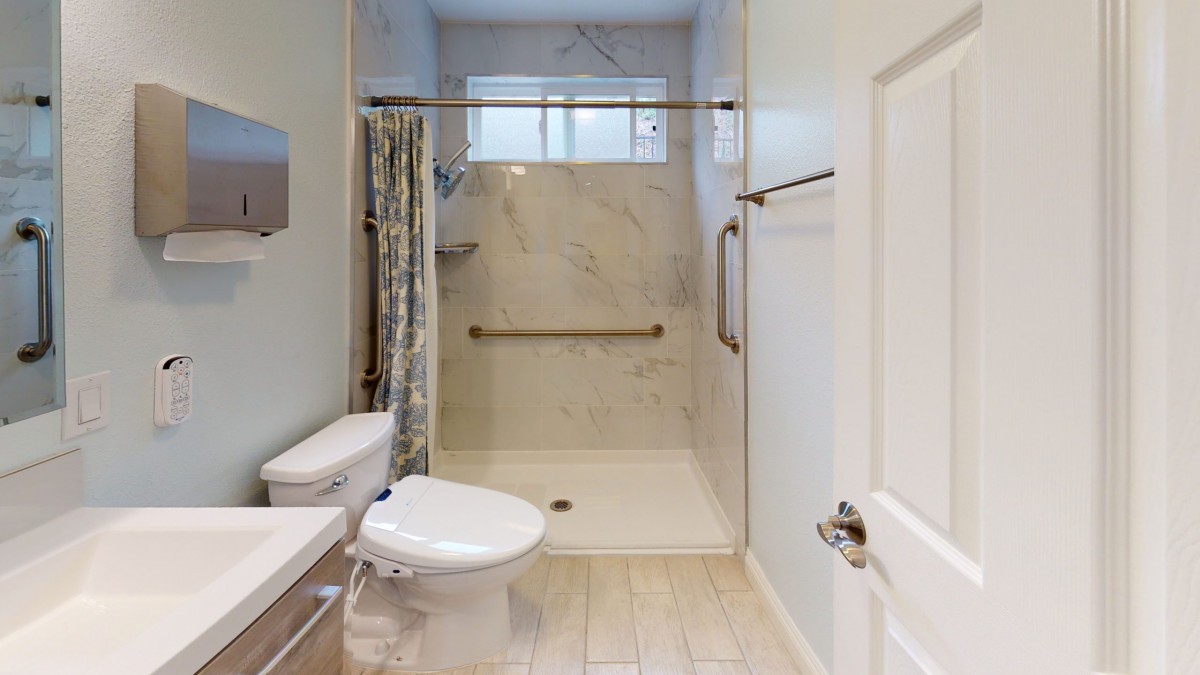 A modern bathroom with a walk-in shower, toilet, and sink.