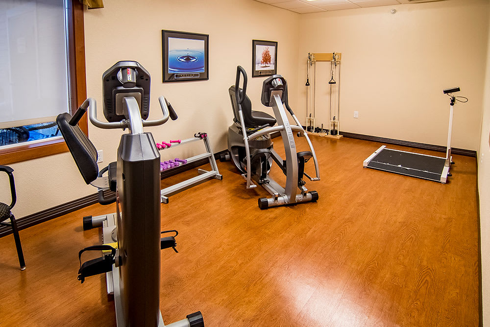 A small indoor gym equipped with exercise machines and a set of dumbbells.