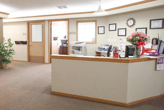 A bright and tidy office reception area with desks, computers, and a waiting area.