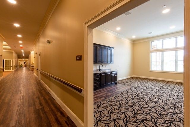 A hallway leading to a room with a patterned carpet and dark cabinets.