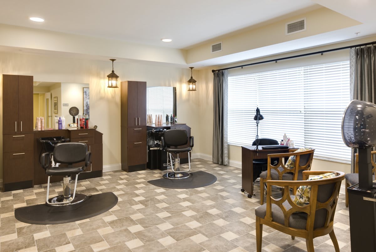 A cozy and well-lit salon interior featuring barber chairs and a large mirror.