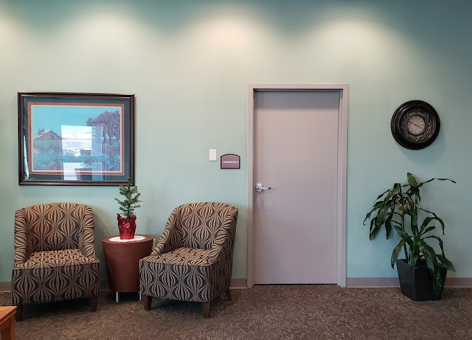 A quiet waiting room with chairs, artwork, and plants.