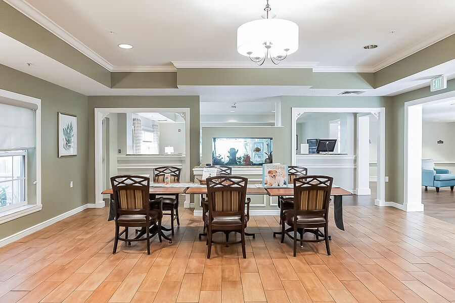 A modern dining room with a wooden table and upholstered chairs, illuminated by a contemporary chandelier.