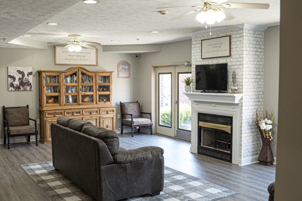A cozy living room with a sofa, armchair, and a fireplace topped with a television.