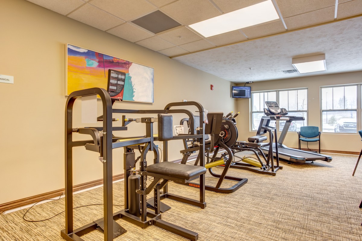 A well-equipped gym room with various exercise machines including treadmills and strength training equipment.