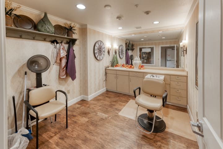 A cozy salon interior featuring a stylist's chair, mirrors, and decorative elements.