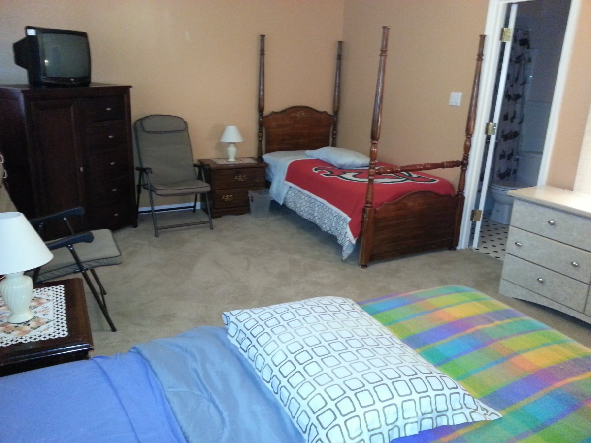 A cozy bedroom with two single beds, a chest of drawers, and a bedside lamp.
