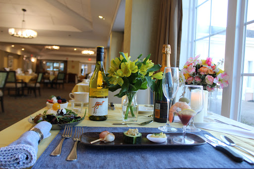 An elegant table set for a fine dining experience featuring wine, sushi, and fresh flowers.