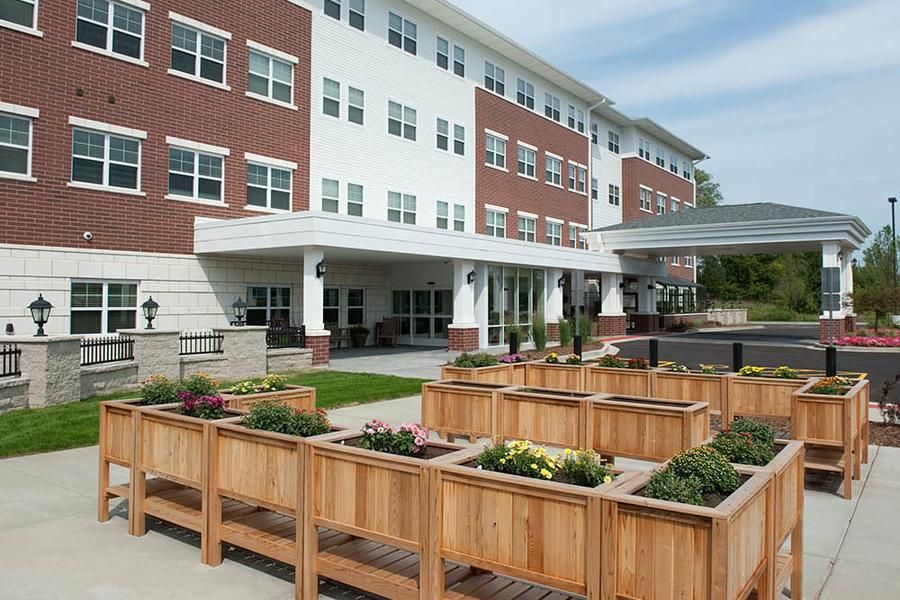 A modern residential building with wooden planters and landscaping in the foreground.