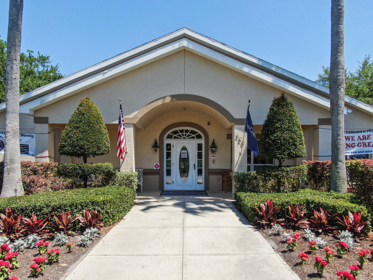 A symmetrical building entrance with a well-maintained garden and flags on either side.