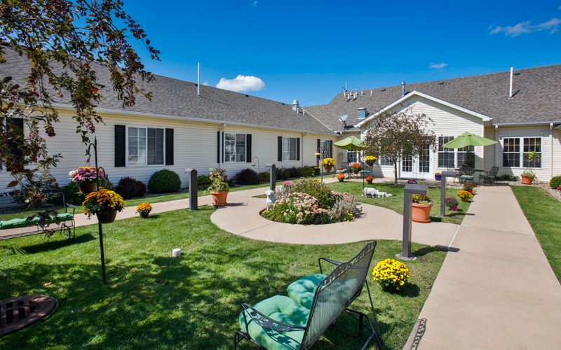 A well-maintained courtyard with lush landscaping and outdoor seating under a clear blue sky.