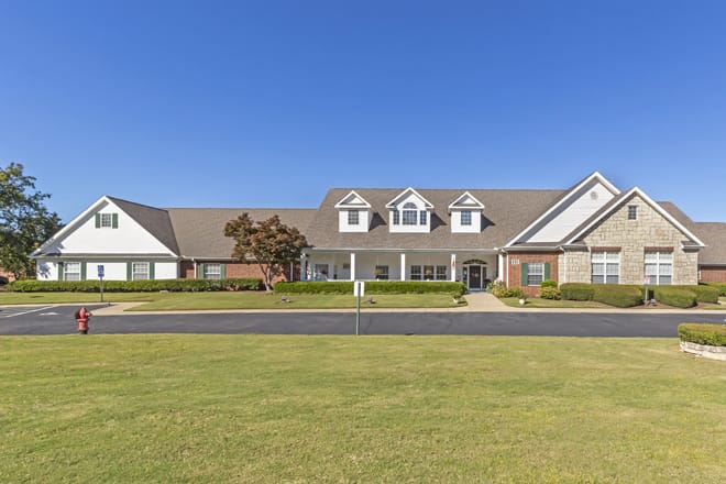 A large residential house with a well-maintained lawn under a clear blue sky.