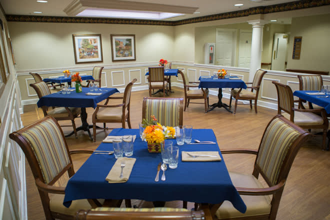 A cozy dining room with blue tablecloths and floral centerpieces.
