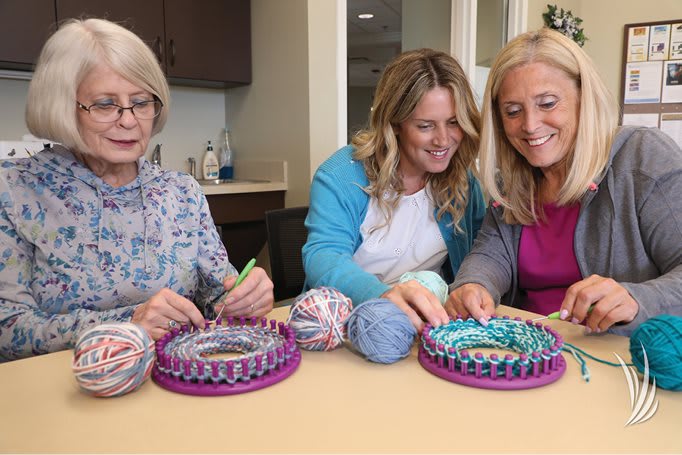 A group of women engaged in knitting and crocheting together at a table.