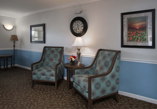 A cozy seating area featuring two patterned chairs, a side table with a lamp, and decorative elements on the walls.