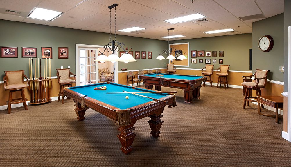 A well-lit recreation room featuring two pool tables and comfortable seating.