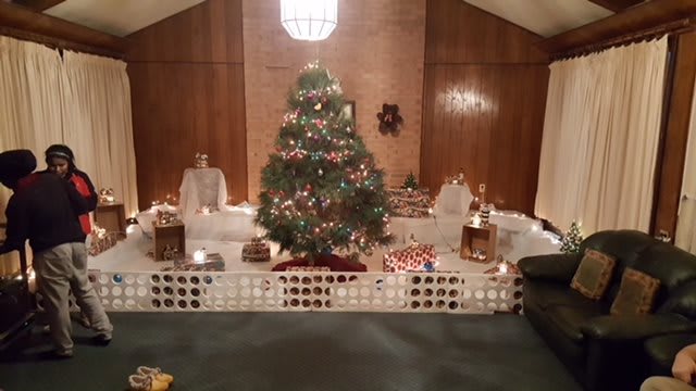 A festive Christmas tree surrounded by presents and holiday decorations in a cozy room.