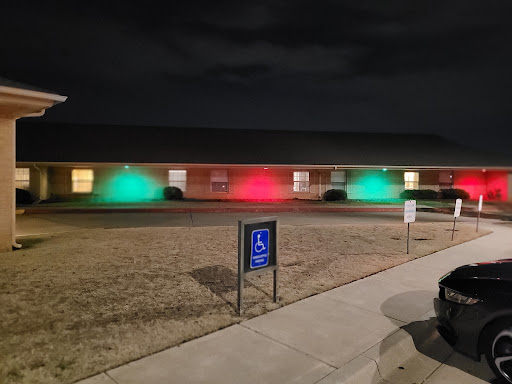 A building illuminated with green and red lights at night, highlighting a welcoming atmosphere.