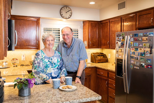 An elderly couple enjoys a moment together in their warm and welcoming kitchen.