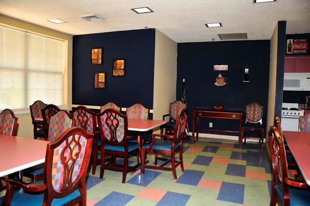 A dining area featuring colorful checkered flooring, elegant chairs, and wall decorations.