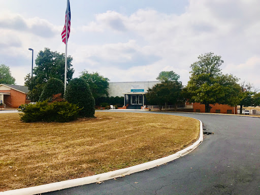 A view of a building with an American flag surrounded by green trees and landscaped grounds.