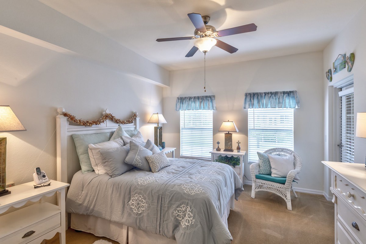 A cozy bedroom with elegant decor, featuring a comfortable bed, charming lamps, and natural light from the windows.