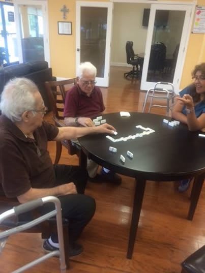 A group of seniors enjoying a game of dominoes at a table indoors.