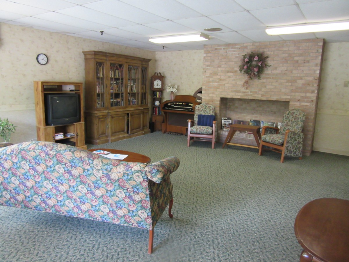 A cozy living room with a floral sofa, television, wooden cabinet, and carpeted flooring.